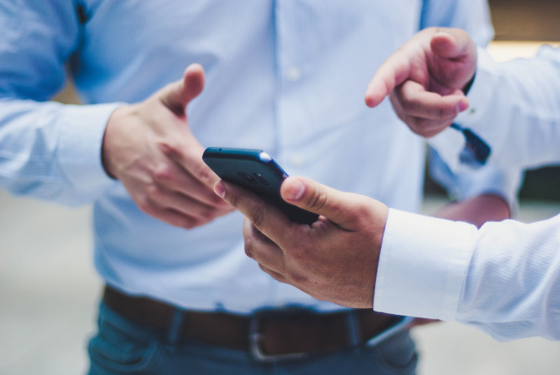 Mobile Optimization : A man pointing to a cell phone with another man 